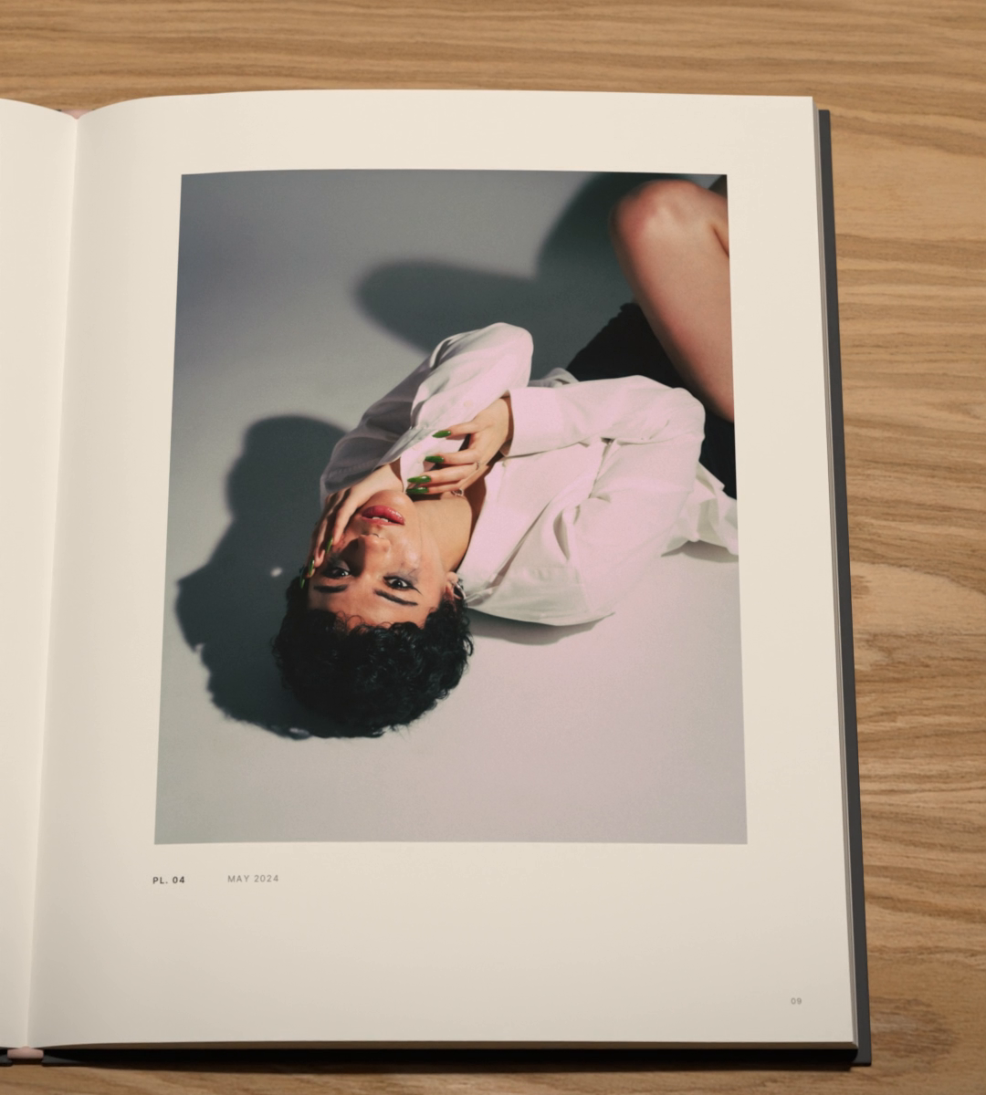 A person in a pale pink shirt lies on a grey floor, one hand at the face, printed with a white border.