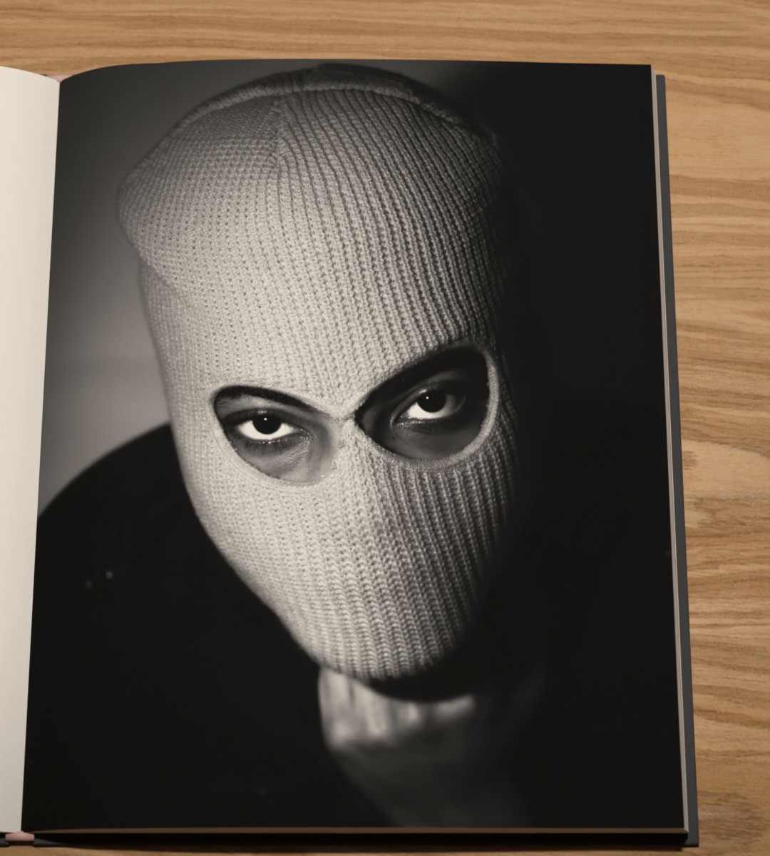 In black and white, a person in a knitted balaclava, only the eyes showing.