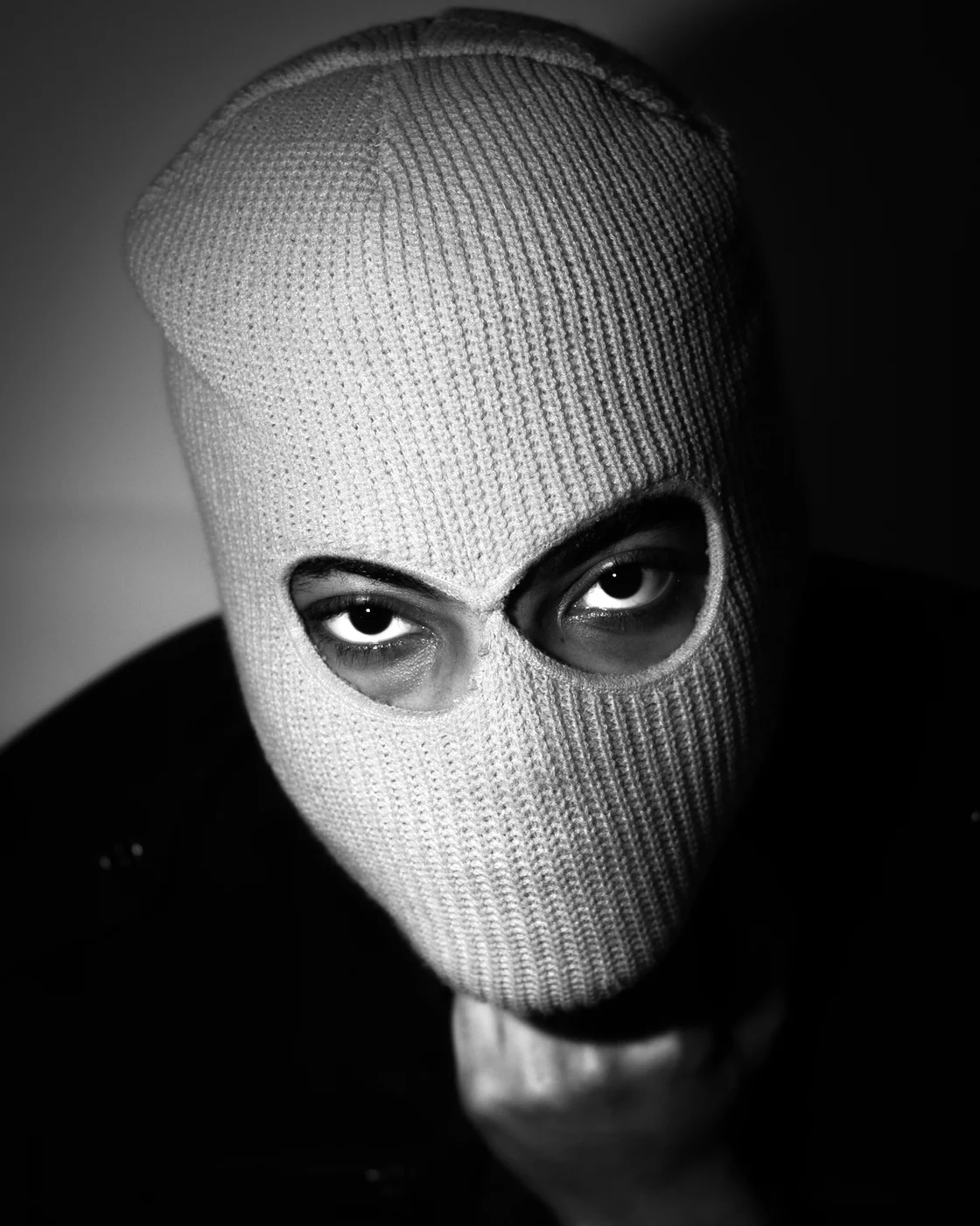 Black and white self-portrait in a knitted balaclava, only the eyes showing.
